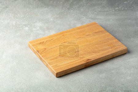 Foto de Tabla de cortar en una mesa de piedra. Fondo culinario. Tabla de cortar de madera vacía, espacio de visualización del producto. - Imagen libre de derechos