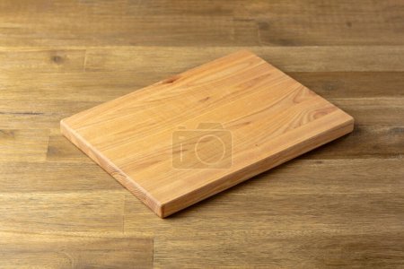 Photo for Cutting board on a wooden table. Culinary background. Empty wooden cutting board, product display space. - Royalty Free Image