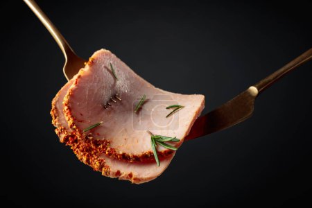 Photo for Spicy sliced ham with rosemary on a black background. - Royalty Free Image