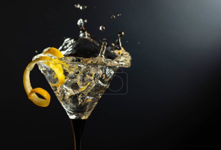 Téléchargez les photos : Verre de cocktail martini sec classique avec écorce de citron sur fond noir. Martini aux éclaboussures. Espace libre pour votre texte. - en image libre de droit