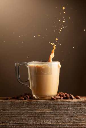 Foto de Una taza de café, café con leche o moca con salpicaduras sobre un fondo marrón. Taza de café y granos de café tostados en una tabla de madera vieja. - Imagen libre de derechos
