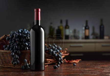 Téléchargez les photos : Bouteille de vin rouge aux raisins bleus sur une table vintage. Dans le comptoir du bar de fond avec diverses bouteilles de vin. Mettre l'accent sur un premier plan. - en image libre de droit