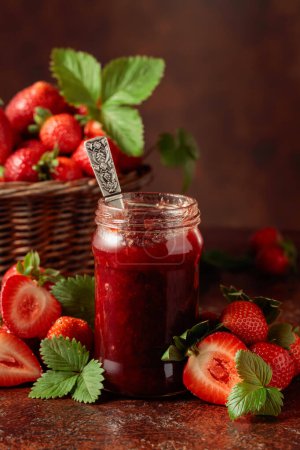 Photo for Strawberry jam and fresh berries with leaves on an old brown table. - Royalty Free Image