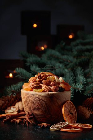 Foto de Frutas secas y frutos secos variados. Bodegón de Navidad con ramas de abeto y velas encendidas. - Imagen libre de derechos
