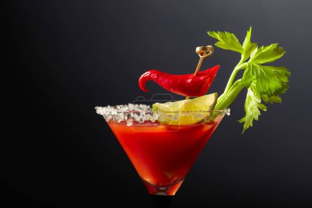 Foto de Cóctel Bloody Mary con apio, lima y pimienta roja. El vidrio está decorado con sal marina. - Imagen libre de derechos