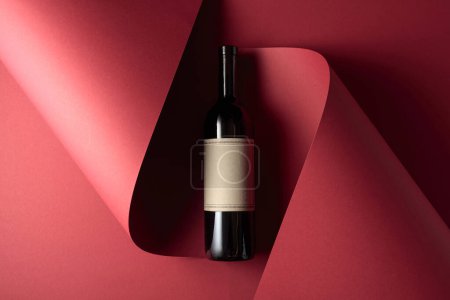 Photo for Bottle of red wine with old empty label on a red background. Copy space for your text, top view. - Royalty Free Image