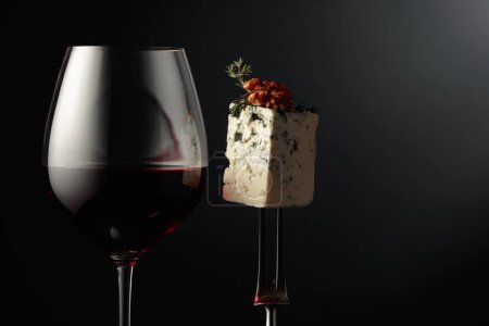 Photo for Glass of red wine and blue cheese. Cheese with walnuts and thyme on a fork. Copy space. - Royalty Free Image