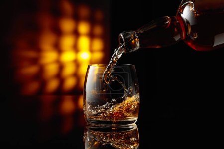 Foto de Verter whisky en un vaso sobre un fondo negro. Copiar espacio. - Imagen libre de derechos