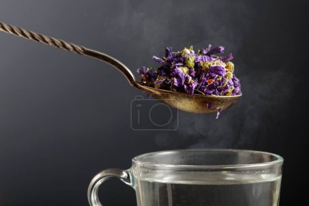 Foto de Flores secas de malva para hacer té de hierbas y taza con agua caliente. Copiar espacio. - Imagen libre de derechos