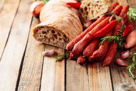 Téléchargez les photos : Saucisses fumées avec oignon, ail, poivre et romarin sur une vieille table en bois. - en image libre de droit