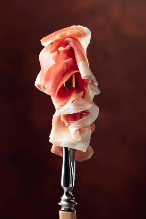 Photo for Thin slices of prosciutto on a fork. - Royalty Free Image