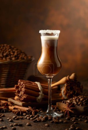 Téléchargez les photos : Crème irlandaise et liqueur de café sur fond brun. Des grains de café, des bâtonnets de cannelle et de l'anis sont éparpillés sur la table. - en image libre de droit