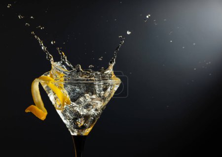 Téléchargez les photos : Verre de cocktail martini sec classique avec écorce de citron sur fond noir. Martini aux éclaboussures. Espace libre pour votre texte. - en image libre de droit