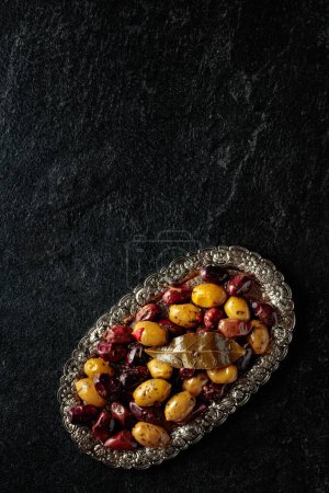 Téléchargez les photos : Olives épicées sur une table en pierre noire. Vue de dessus. Espace de copie. - en image libre de droit