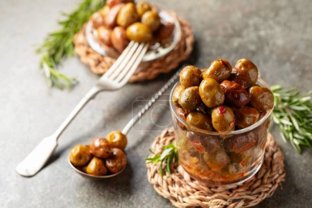 Téléchargez les photos : Olives épicées dans un bol en verre. Bol avec olives conservées et brindilles de romarin sur une table en pierre. - en image libre de droit