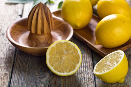 Foto de Limones maduros y exprimidor sobre una vieja mesa de madera
 . - Imagen libre de derechos
