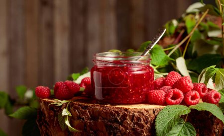 Photo for Jar of raspberry jam and fresh berries with leaves on a pine stump. Copy space. - Royalty Free Image