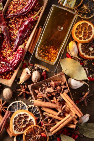 Photo for Bottle of olive oil and various spices on an old wooden table. Top view. - Royalty Free Image