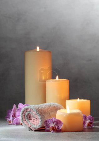 Téléchargez les photos : Serviettes, fleurs d'orchidée et bougies allumées. Concept de spa avec espace de copie. - en image libre de droit