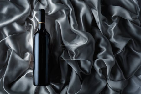 Téléchargez les photos : Bottle of red wine on a satin background. Top view. - en image libre de droit