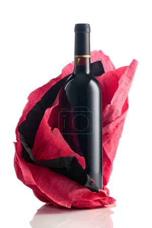 Foto de Botella de vino tinto con papel crepé rojo y negro arrugado aislado sobre fondo blanco. - Imagen libre de derechos