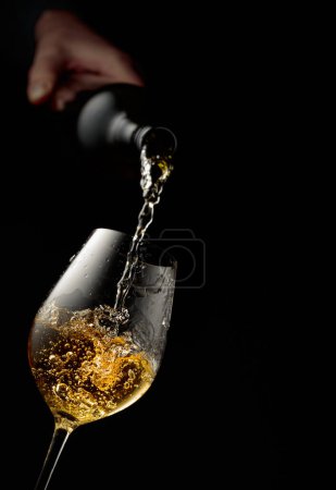 Foto de Vierte vino blanco en una copa. Fondo negro con espacio de copia. - Imagen libre de derechos