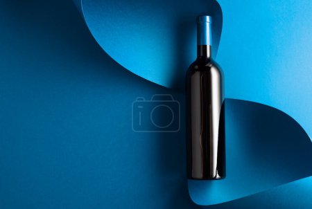 Téléchargez les photos : Bouteille de vin rouge sur fond bleu. Vue du dessus. - en image libre de droit