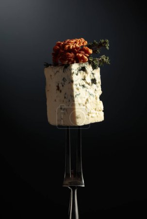 Photo for Blue cheese with walnuts and thyme on a fork. - Royalty Free Image