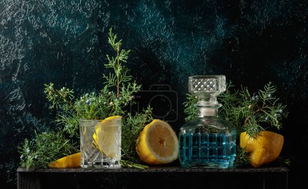 Téléchargez les photos : Cocktail gin-tonic avec glace, citron et romarin dans un verre congelé. Une boisson rafraîchissante aux branches de genièvre sur fond vintage bleu foncé. Espace de copie. - en image libre de droit