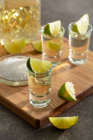 Photo for Gold tequila with sea salt and lime slices on a cutting board. - Royalty Free Image