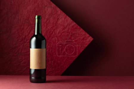 Téléchargez les photos : Bouteille de vin rouge sur fond rouge. Sur une vieille étiquette vide. Copiez l'espace pour votre texte. - en image libre de droit