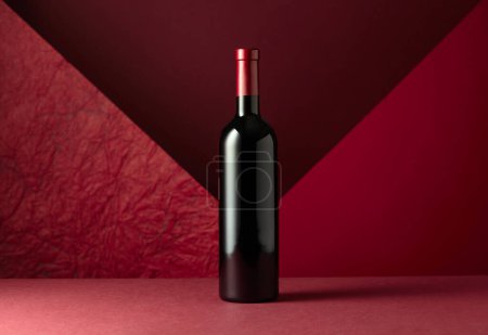 Photo for Bottle of red wine on a red background. Copy space for your text. - Royalty Free Image