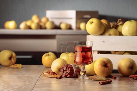 Téléchargez les photos : Pommes fraîches juteuses dans une boîte en bois et verre de jus de pomme sur une table de cuisine. - en image libre de droit