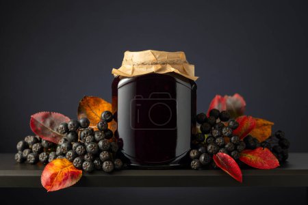 Photo for Chokeberry jam and fresh berries with leaves on a black background. - Royalty Free Image