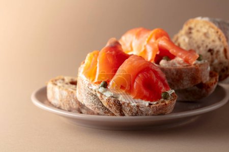 Photo for Sandwich with smoked trout, cream cheese, and capers on a beige background. - Royalty Free Image