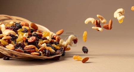 Photo for Flying dried fruits and nuts. The mix of dried nuts and raisins on a beige background. Copy space. - Royalty Free Image