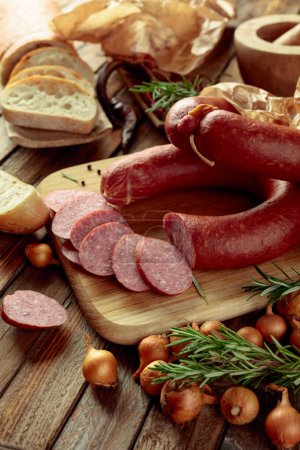 Téléchargez les photos : Saucisse fumée au romarin, oignon et poivre. Saucisse avec pain et épices sur une vieille table en bois. - en image libre de droit