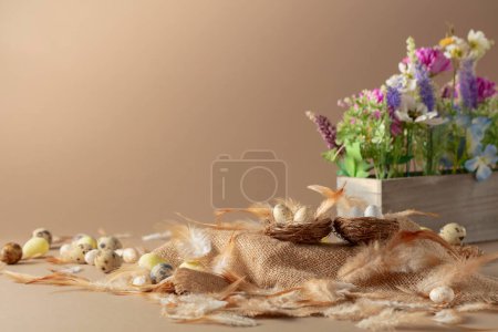 Photo for Easter composition with eggs, feathers, and spring flowers on a beige background. Copy space. - Royalty Free Image