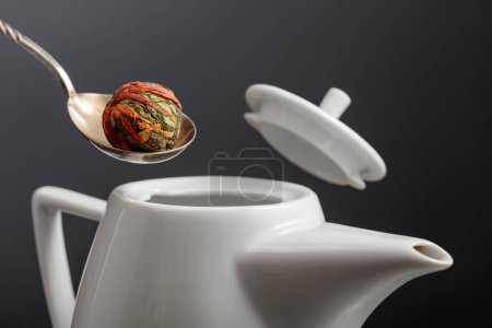 Téléchargez les photos : Boule de thé vert chinoise avec des fleurs de souci (calendula) sont versés dans la théière. Concentration sélective. - en image libre de droit