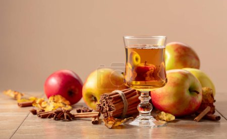 Photo for Apple juice with apples, cinnamon, and anise on a beige background. Copy space. - Royalty Free Image