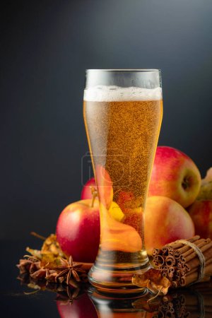 Photo for Apple cider in high glass. Fresh drink with apples, cinnamon, and anise on a black background. - Royalty Free Image