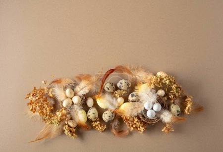 Foto de Composición de Pascua con huevos de codorniz, plumas y flores secas. Vista superior. Fondo beige con espacio de copia. - Imagen libre de derechos