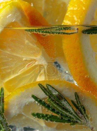 Foto de Cóctel gin-tonic con rodajas de limón y romero. Macro tiro. - Imagen libre de derechos