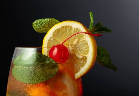 Téléchargez les photos : Cocktail d'été froid et rafraîchissant Cuba libre avec tranches de citron, cerise et menthe sur fond noir. - en image libre de droit