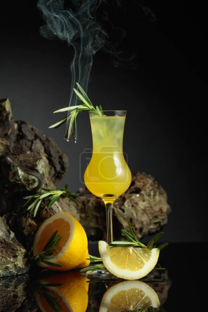 Photo for Traditional homemade lemon liqueur limoncello and fresh citrus on the black reflective background. Italian traditional liqueur limoncello with lemon slices and smoldering rosemary branch. - Royalty Free Image