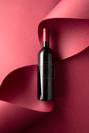 Photo for Bottle of red wine on a red background. Top view. - Royalty Free Image