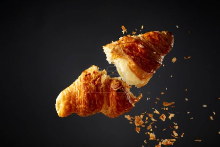 Foto de Croissant recién horneado en el aire sobre un fondo negro. - Imagen libre de derechos