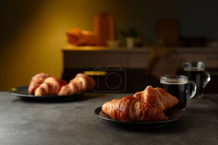 Foto de Croissants recién horneados y café negro en una mesa de cocina. Enfoque selectivo. - Imagen libre de derechos