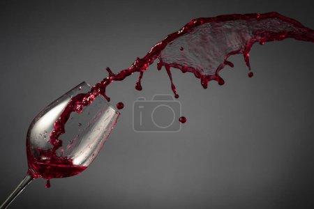 Photo for Glass and red wine splash on a dark background. Copy space. - Royalty Free Image