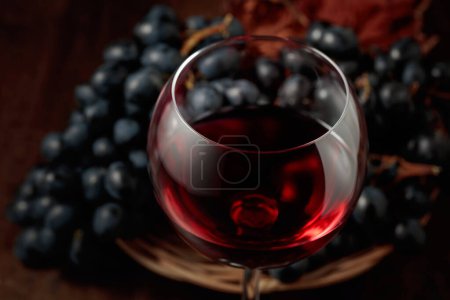 Photo for Red wine and blue grapes on an old wooden table. Selective focus. - Royalty Free Image